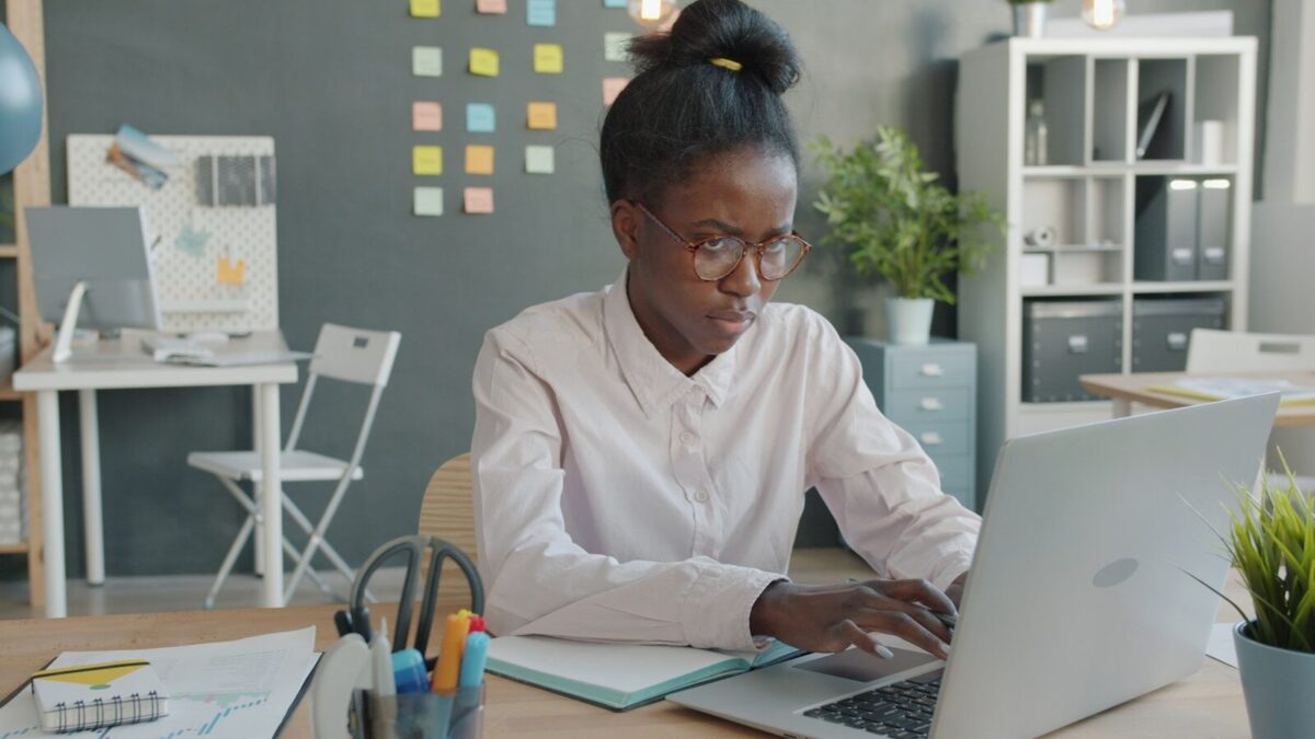 Woman working on a laptop at a desk.